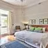 Bright bedroom with large bed green pillows and open door to outside