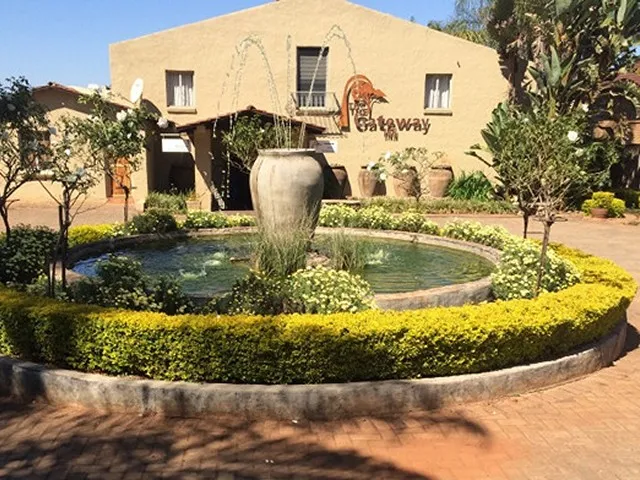 Circular fountain with large pot surrounded by yellow flowers in front of a building