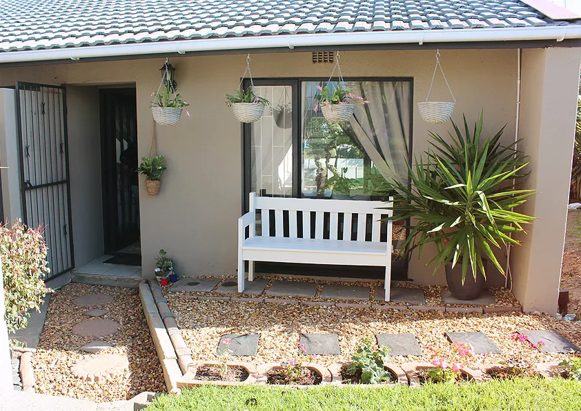 White bench in front of a house with potted plants and a tiled roof