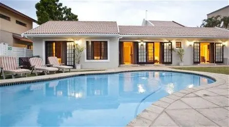 Modern house with pool lounge chairs and evening lighting