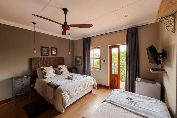 Cozy bedroom with a large bed ceiling fan and a view of greenery