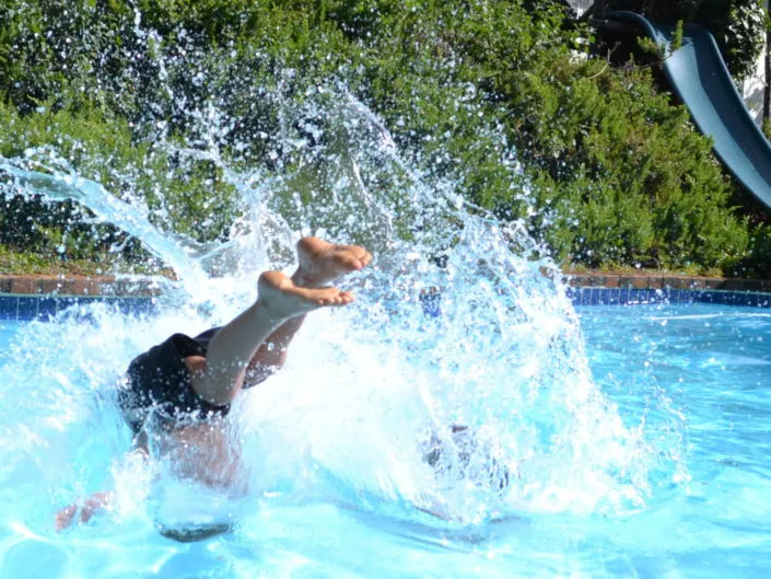 Person splashing into a swimming pool with water spraying upwards