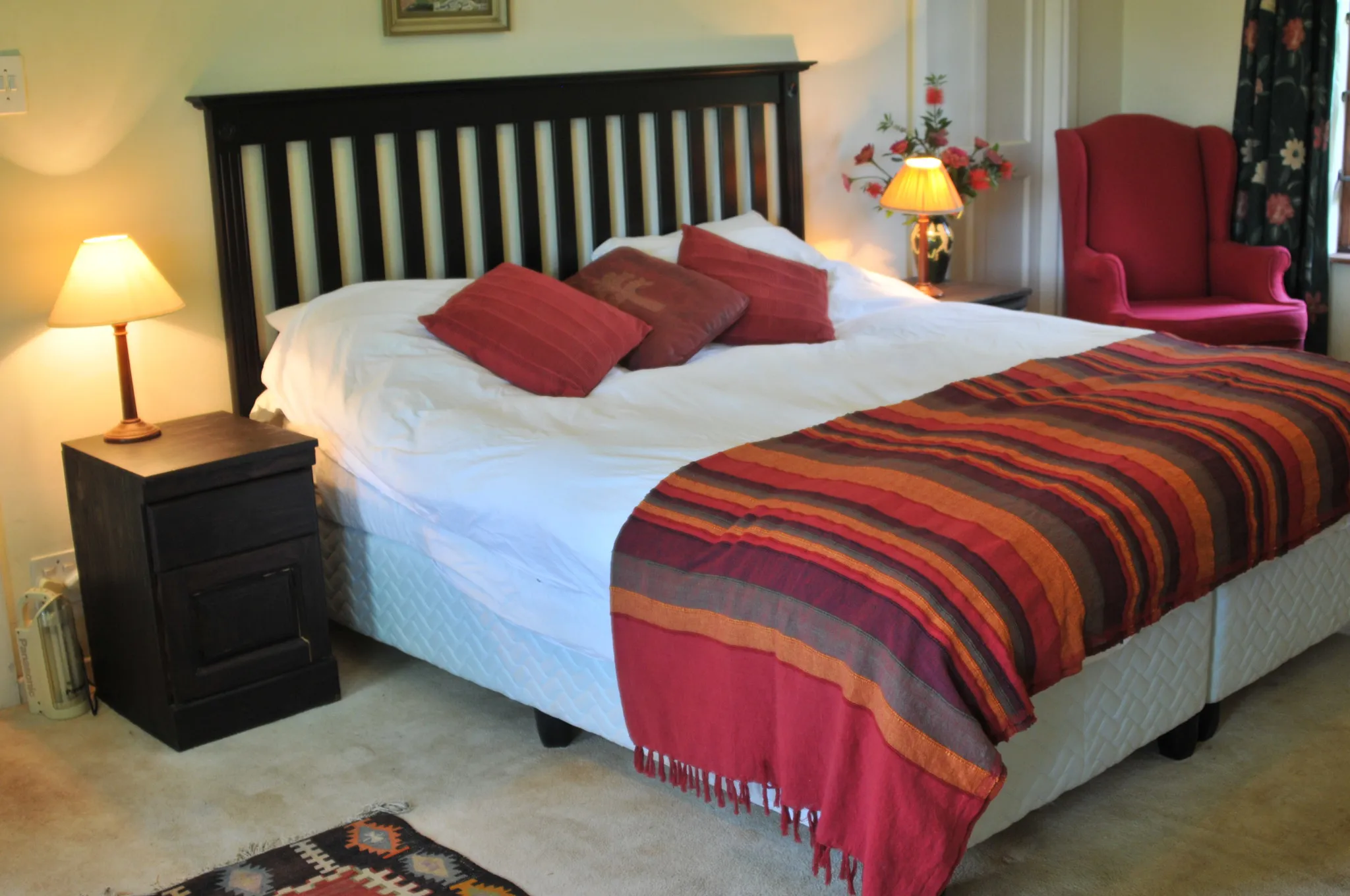 Cozy bedroom with a large bed red pillows and striped blanket