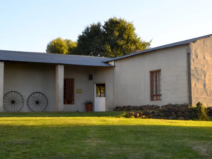 Singlestory house with a veranda two wagon wheels and a grassy lawn