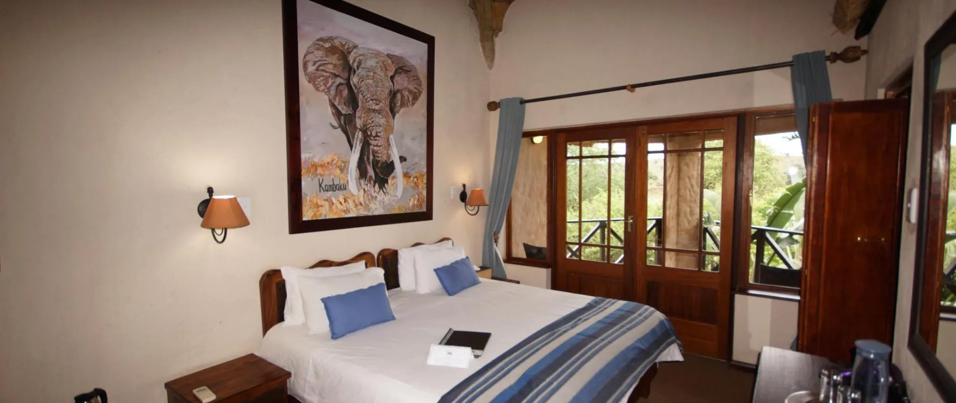 Cozy bedroom with large bed elephant artwork and wooden balcony doors