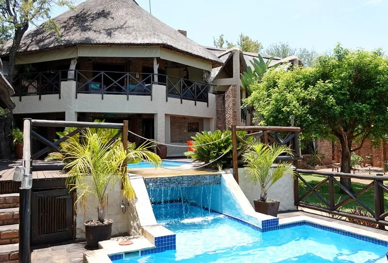 A luxurious house with a pool and waterfall in a tropical garden setting