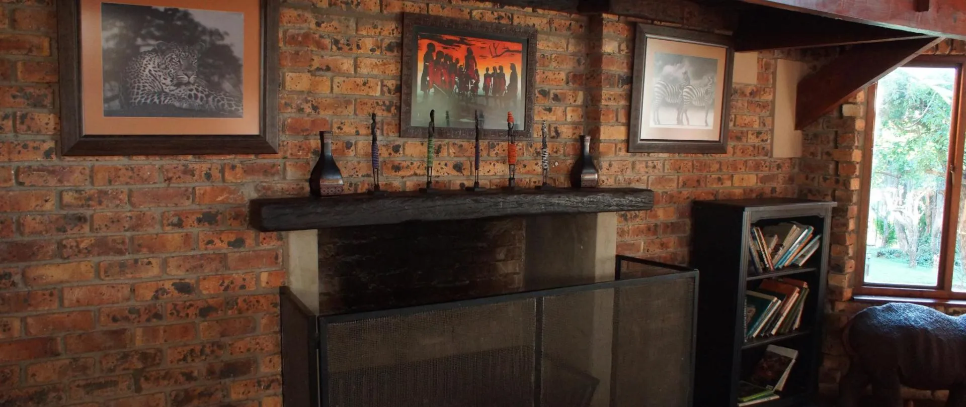Brick fireplace with artwork bottles and bookshelves in a cozy room