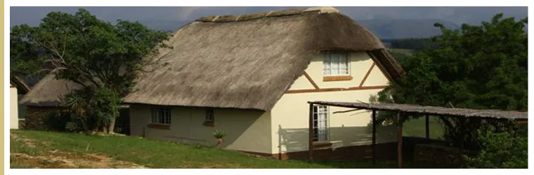 Thatchedroof house with a veranda in a rural setting surrounded by trees