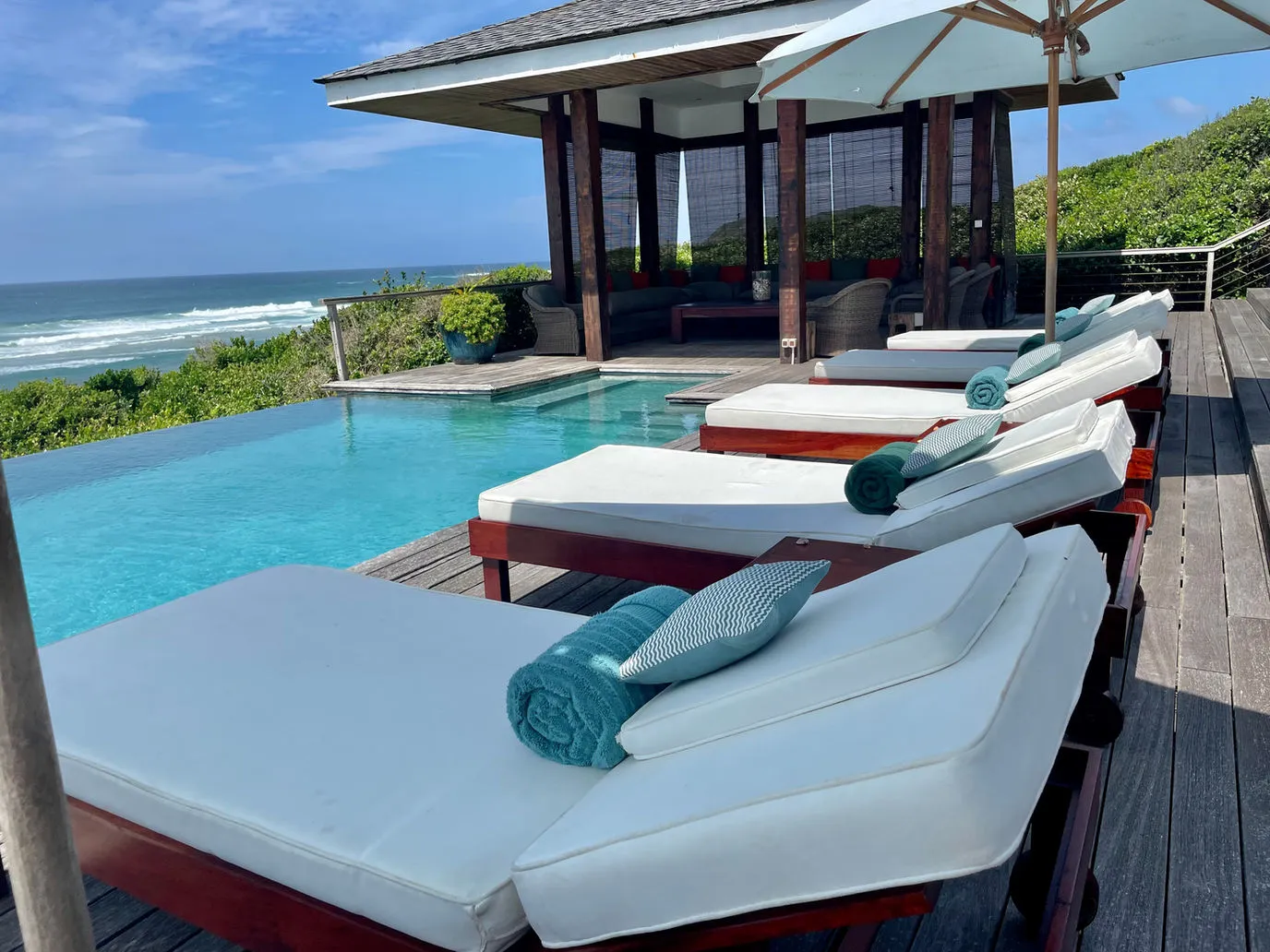 Wooden lounge chairs with towels by an infinity pool overlooking the ocean