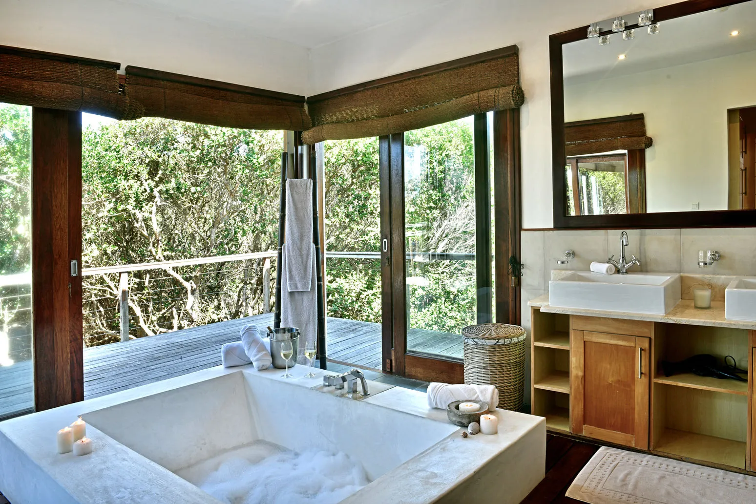Modern bathroom with large bathtub wooden cabinets and large windows with forest view