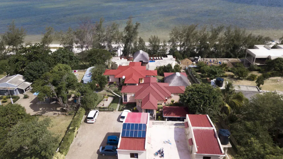 Aerial view of beachfront houses with red roofs and surrounding greenery