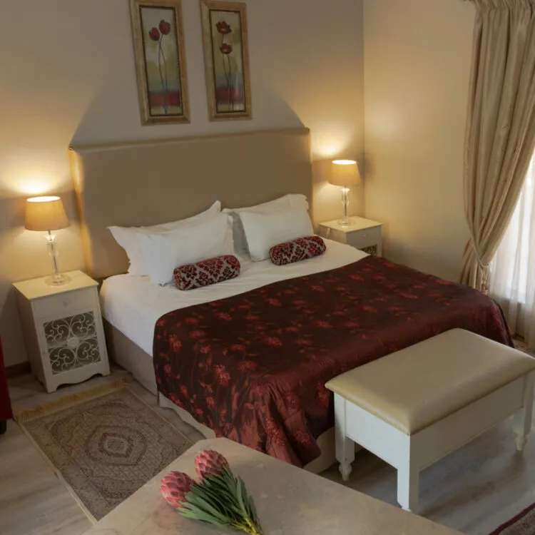 Cozy bedroom with a large bed bedside tables and floral artwork