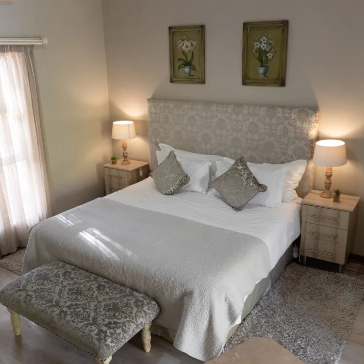 Cozy bedroom with a neatly made bed and floral artwork on the wall