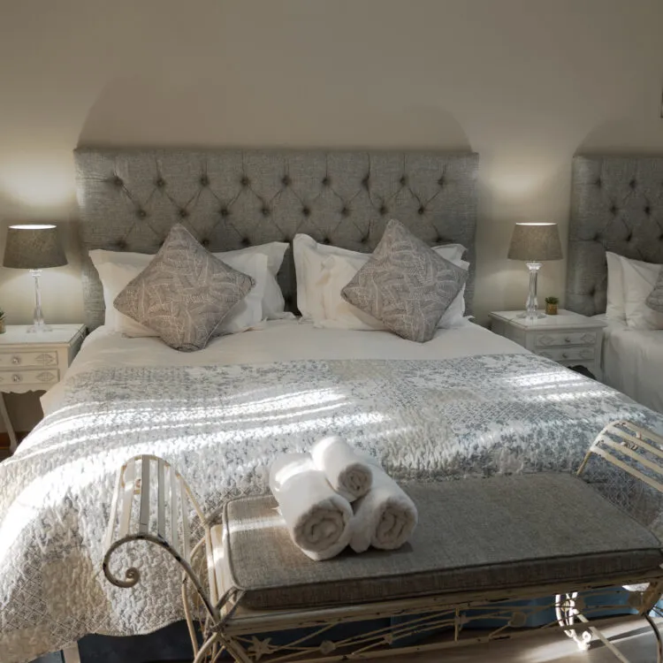 Cozy bedroom with a large bed pillows and a bench with rolled towels