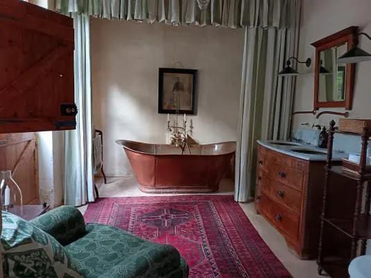 Vintage bathroom with copper tub wooden cabinet and patterned rug