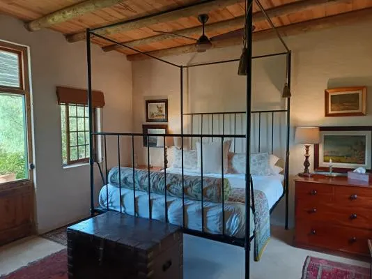 Fourposter bed in a cozy rustic bedroom with wooden ceiling and artwork