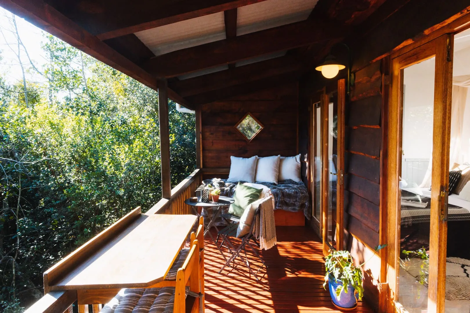 Wooden balcony with table chairs and cozy seating area overlooking greenery
