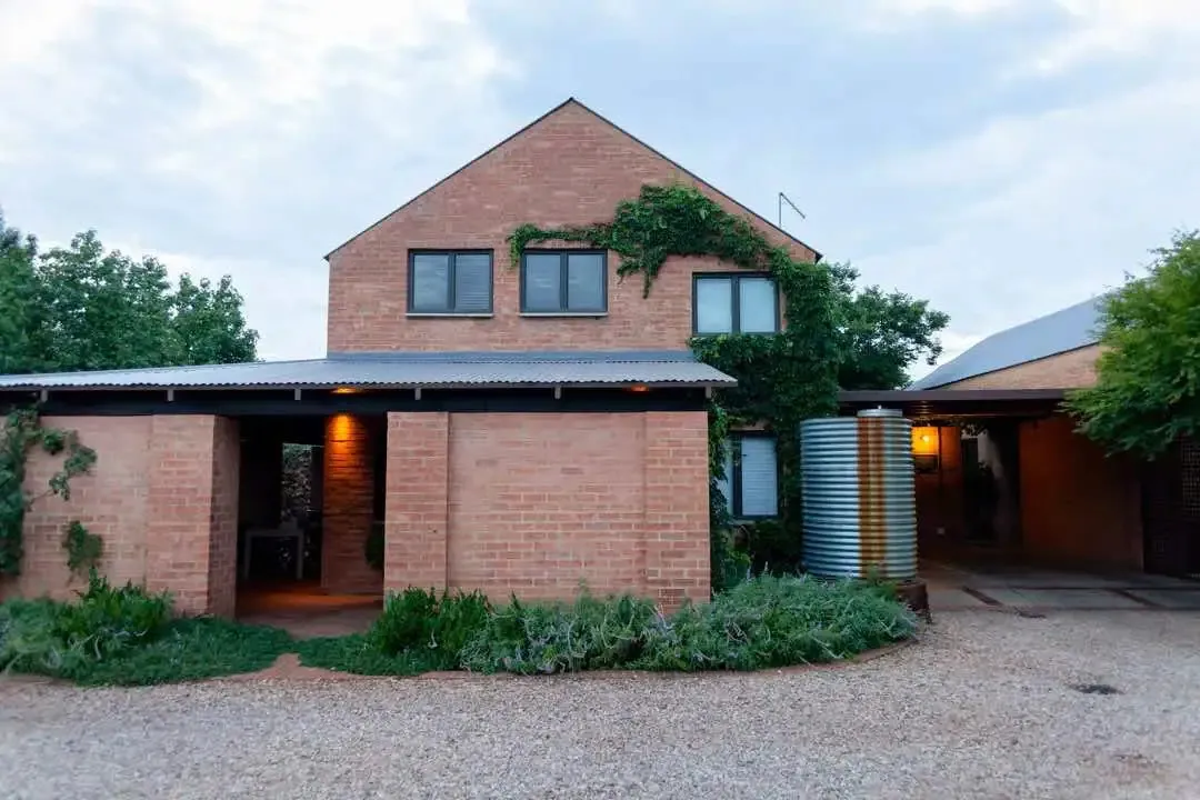 Modern brick house with greenery and gravel driveway at dusk