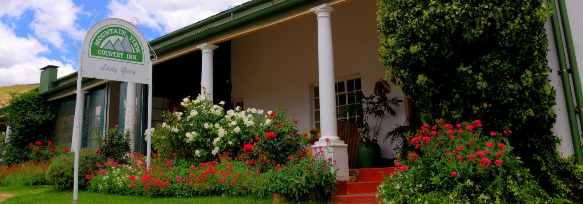 Country inn with a sign white columns and colorful flowers in front