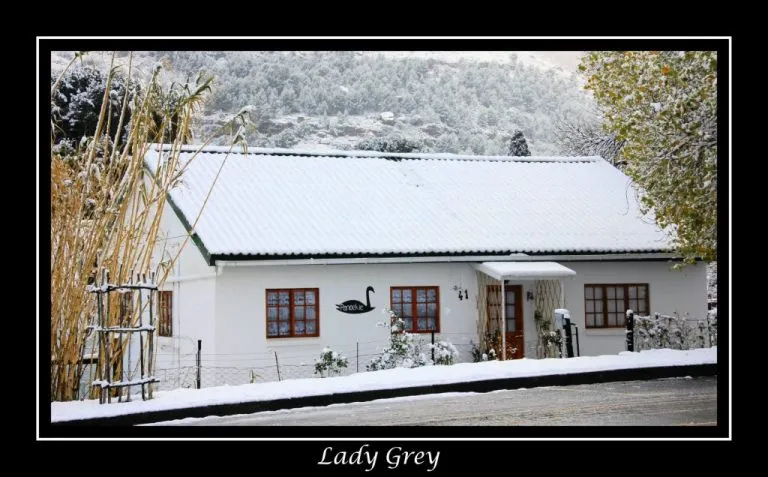 Snowcovered house with a white roof and wooden windows in a snowy landscape