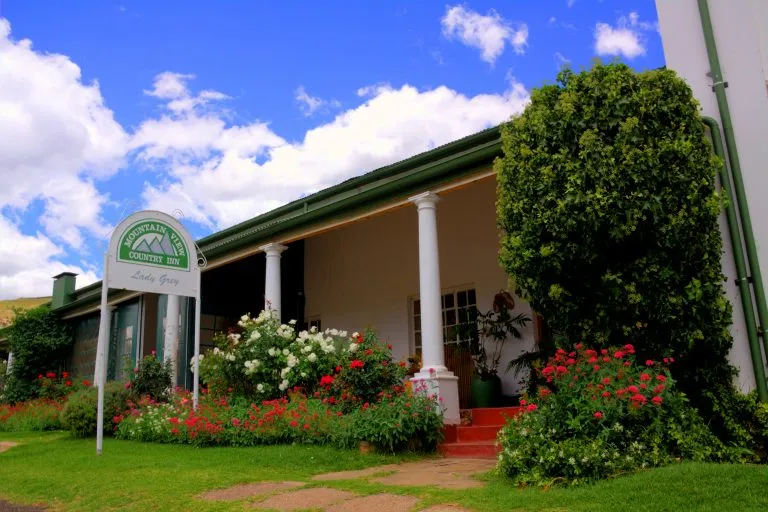 A house with a garden sign and verandah under a blue sky