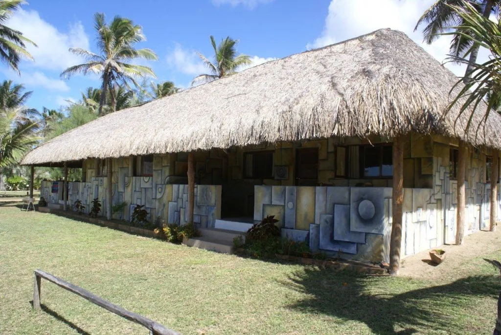 Thatchroofed building with colorful geometric murals in a tropical setting