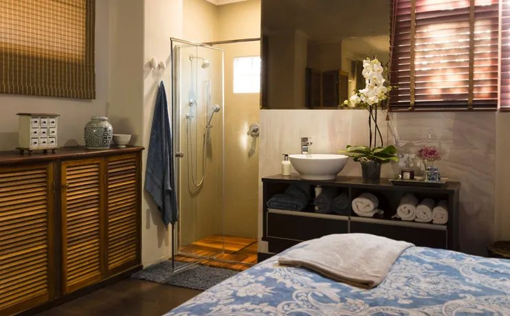 Modern bathroom with shower sink and bed with blue patterned blanket