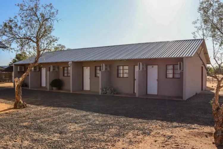 Singlestory building with multiple doors and windows surrounded by trees and gravel