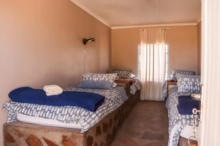 Two single beds in a small tidy bedroom with a window