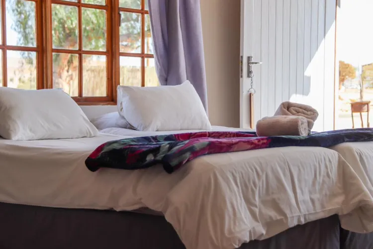Bed with white pillows and colorful blanket in a room with open door