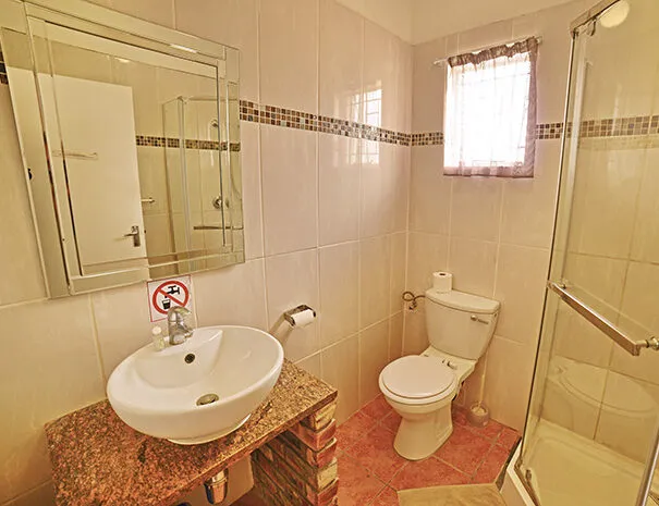 Small bathroom with sink toilet and shower featuring tiled walls and floor
