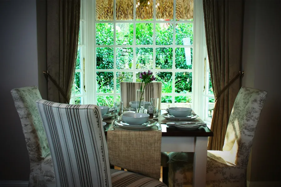 Dining table set for four with a window view of greenery