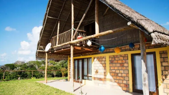 A thatchedroof house with a balcony colorful balloons and a scenic background