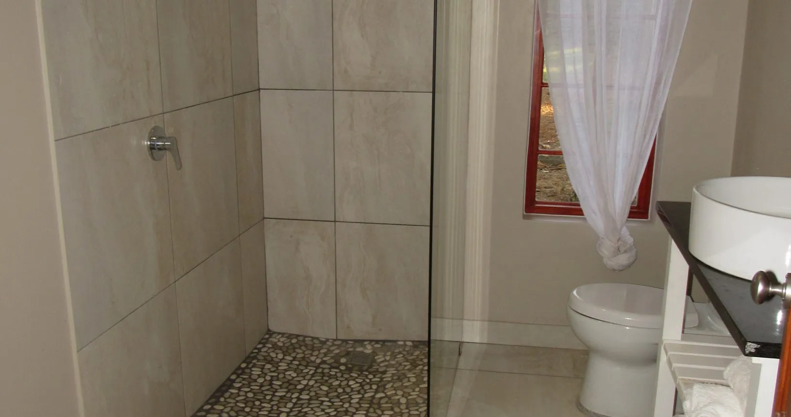 Modern bathroom with shower toilet and sink featuring tiled walls and window