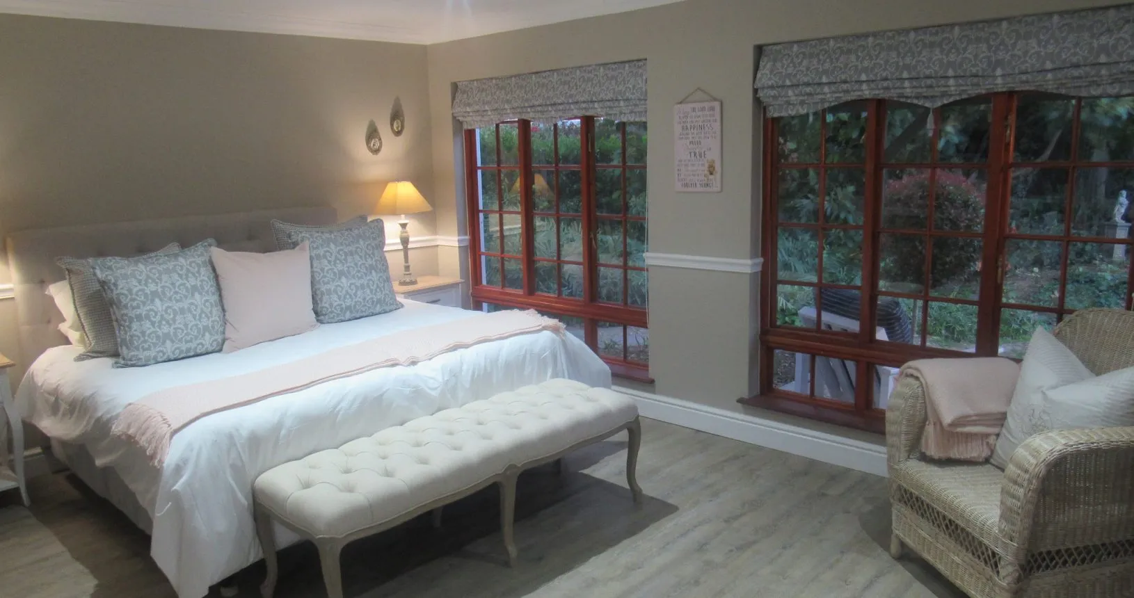 Bedroom with large bed tufted bench and armchair by large windows