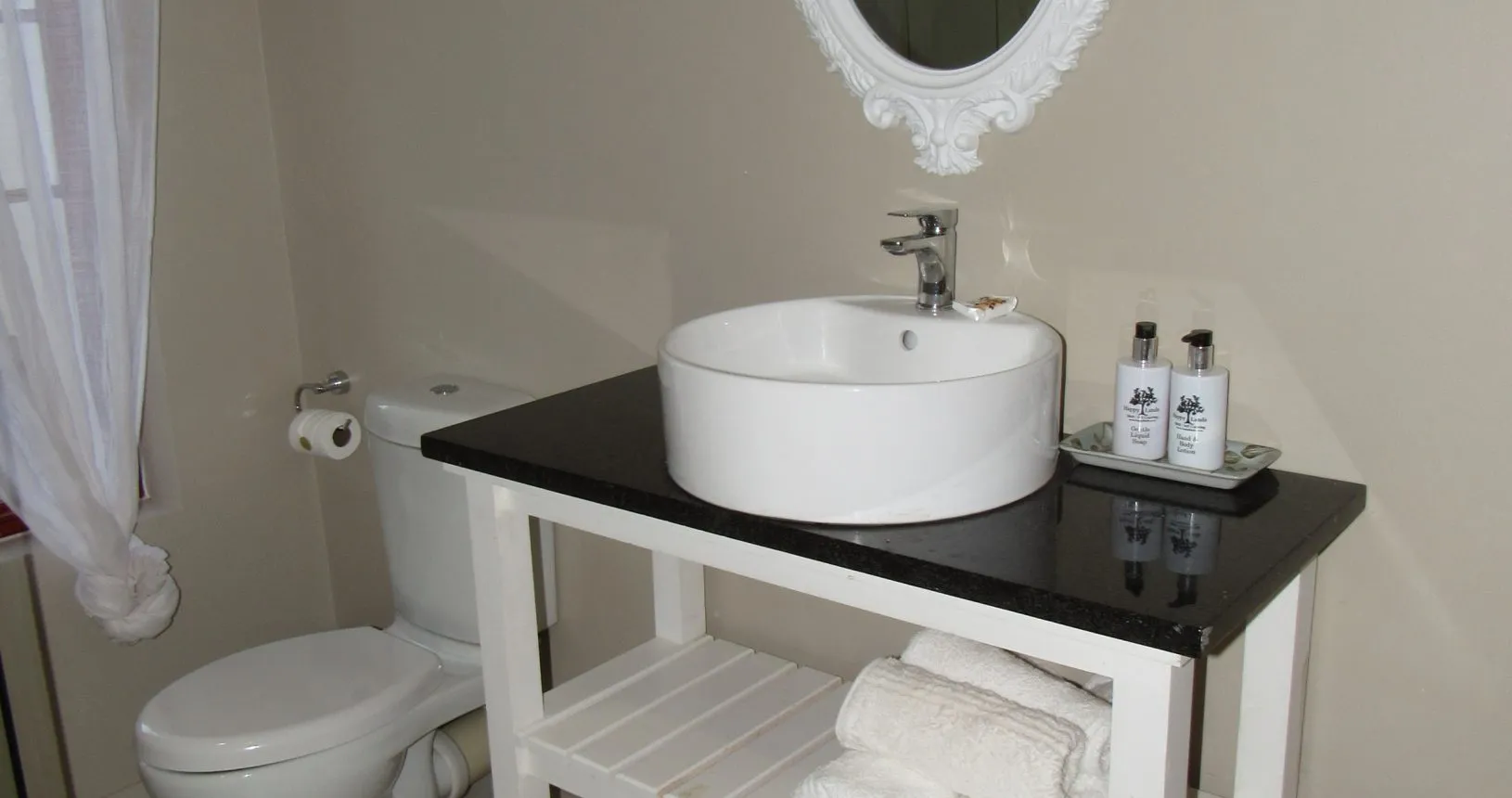 Modern bathroom with white fixtures black countertop and towels on a shelf