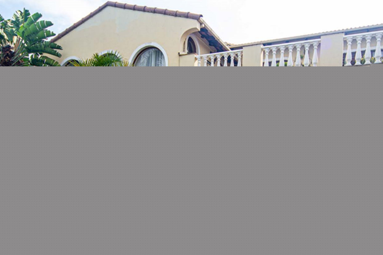 Beige house with redtiled roof and white balcony railing
