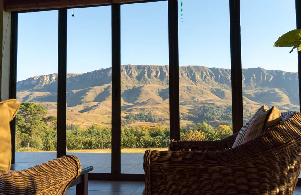 Wicker chairs in front of large windows with mountain view