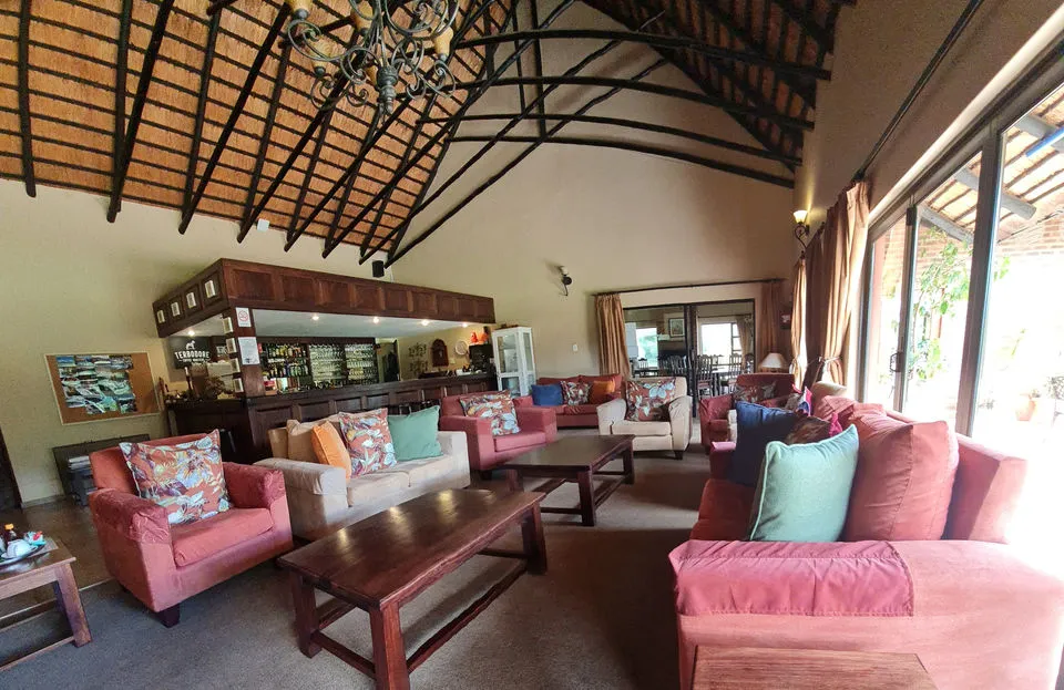 Cozy lounge with sofas coffee tables and a bar area under a wooden ceiling