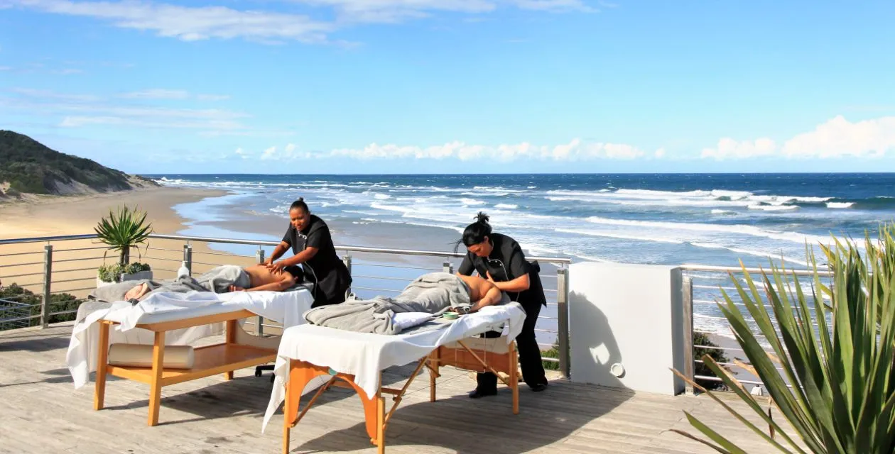 Two masseuses giving massages on a deck overlooking the ocean
