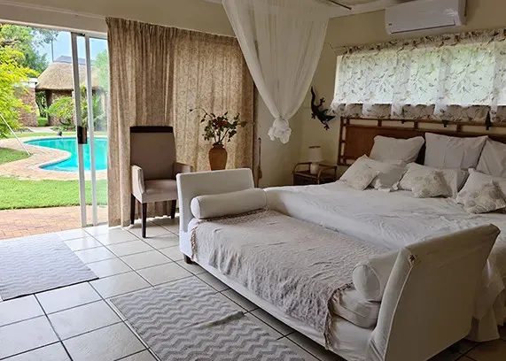 Bedroom with a large bed chaise lounge and view of a pool outside