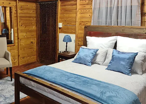 Wooden bedroom with a large bed blue pillows and a blue throw blanket