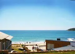 Beach with people walking buildings and clear blue sky and sea