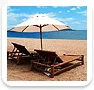 Beach chairs and umbrella on sandy shore with blue sky and ocean background
