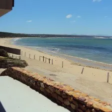 Beach view from a stone wall with clear blue sky and calm sea