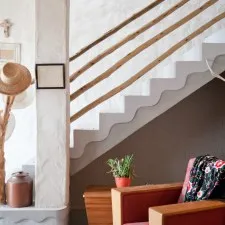 Staircase with wooden handrail potted plant and chair with patterned blanket
