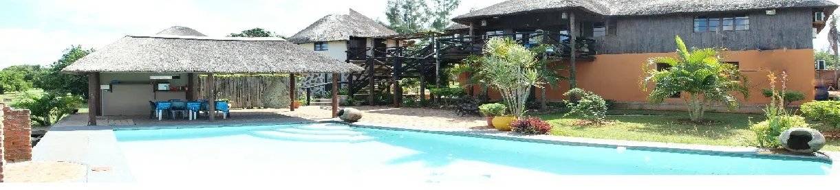Swimming pool with thatchedroof structures and tropical landscaping in a resort setting