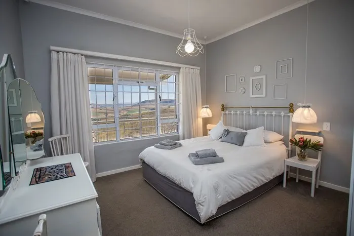 Cozy bedroom with a large window white bed and grey walls