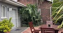 Wooden table and chairs in a small garden area beside a brick building