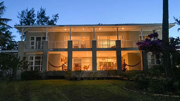 Modern twostory house with large windows and hammocks lit up at dusk